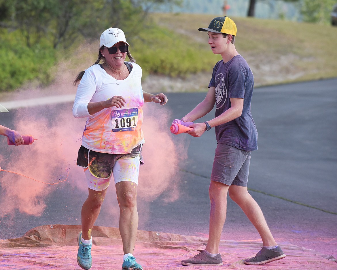 Jodi Riedel gets splashed with orange and purple colors Saturday morning during the Great Fish Community Challenge Color Run through Whitefish. (Heidi Desch/Whitefish Pilot)