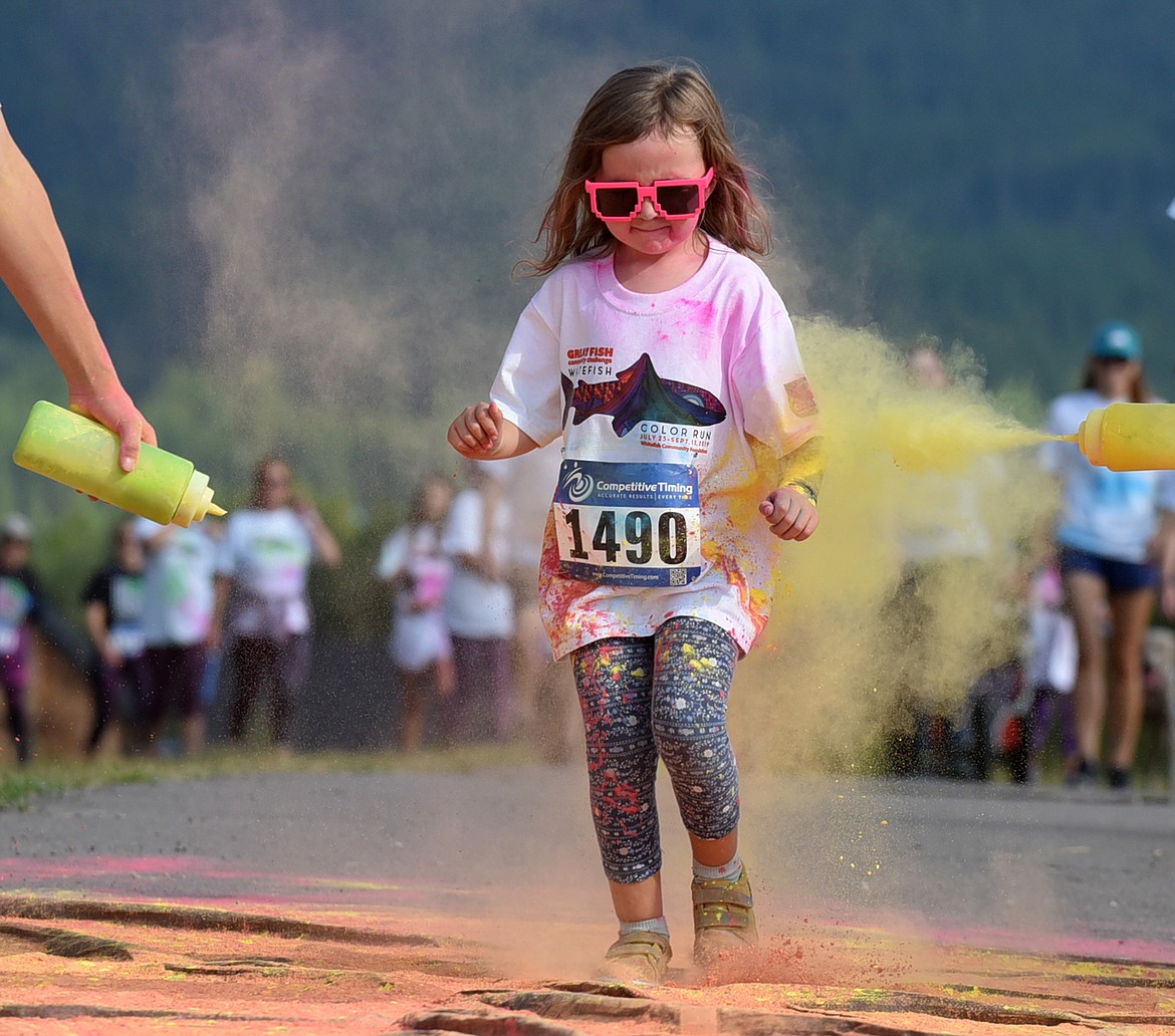 Cora Delaloye, 6, runs through the green and yellow station Saturday morning during the Great Fish Community Challenge Color Run through Whitefish. (Heidi Desch/Whitefish Pilot)