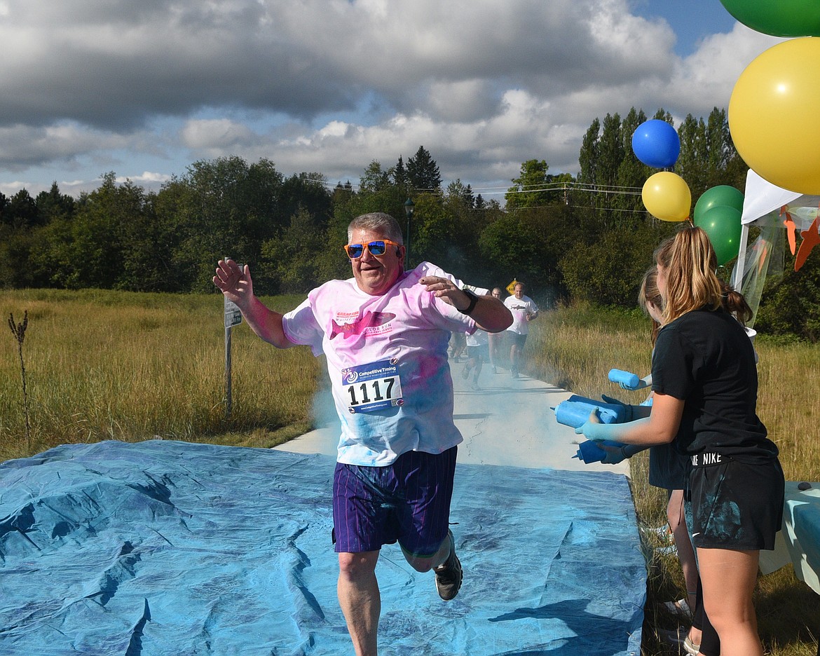 Eric Hale dashes through the blue station Saturday morning during the Great Fish Community Challenge Color Run through Whitefish. (Heidi Desch/Whitefish Pilot)