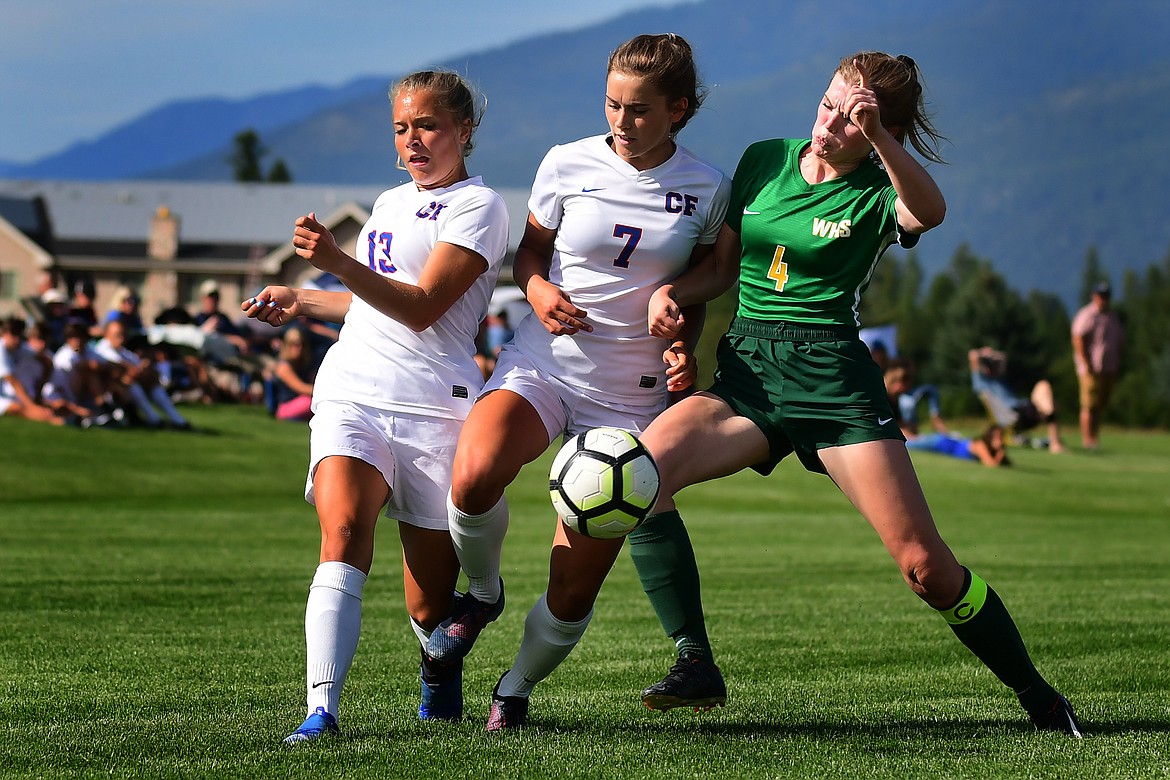 Wildkats Sydney Mann (13) and Maddie Robison (7) battle Whitefish&#146;s Mary Peterson for the ball.