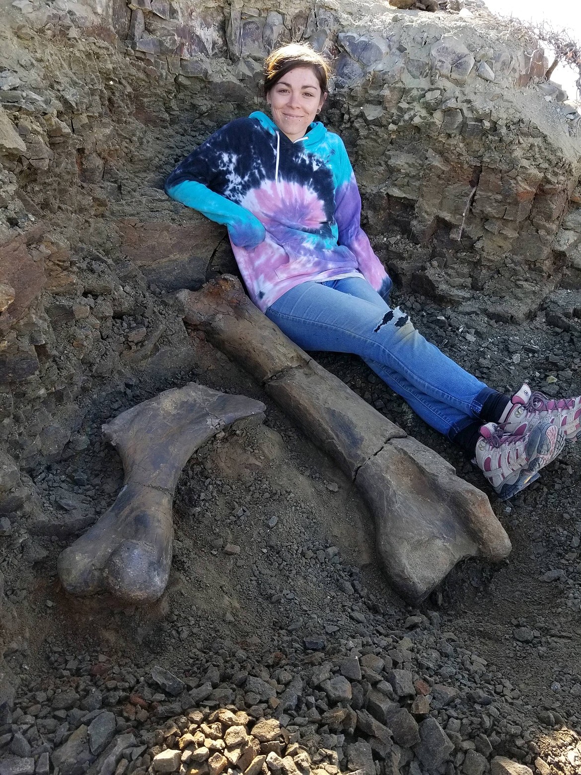 Chantel Ibach sits next to a Hypacrosaurus femur and humerus from the Montana Two Medicine Formation. (Courtesy of NorthWest Montana Fossils)