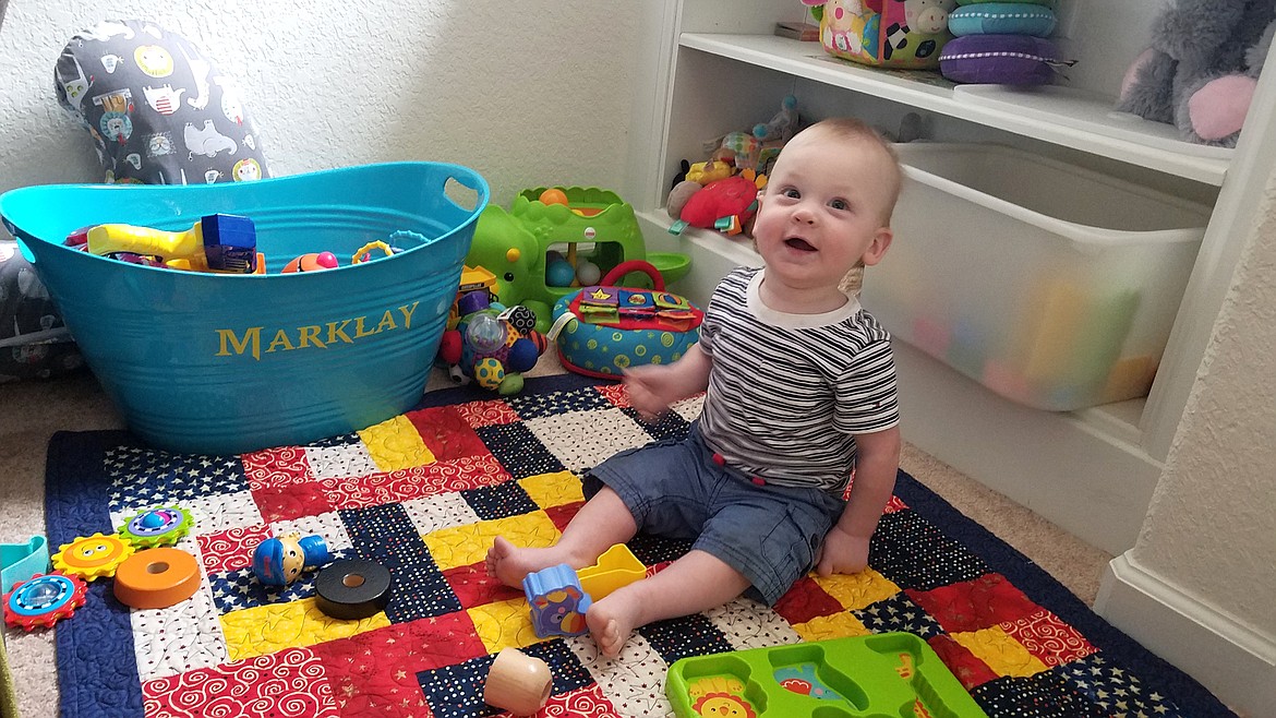 The son of a USS Montana crewmember smiles atop a quilt gifted to him by the Bigfork Piecemakers Quilt Guild. (Courtesy of USS Montana Committee)