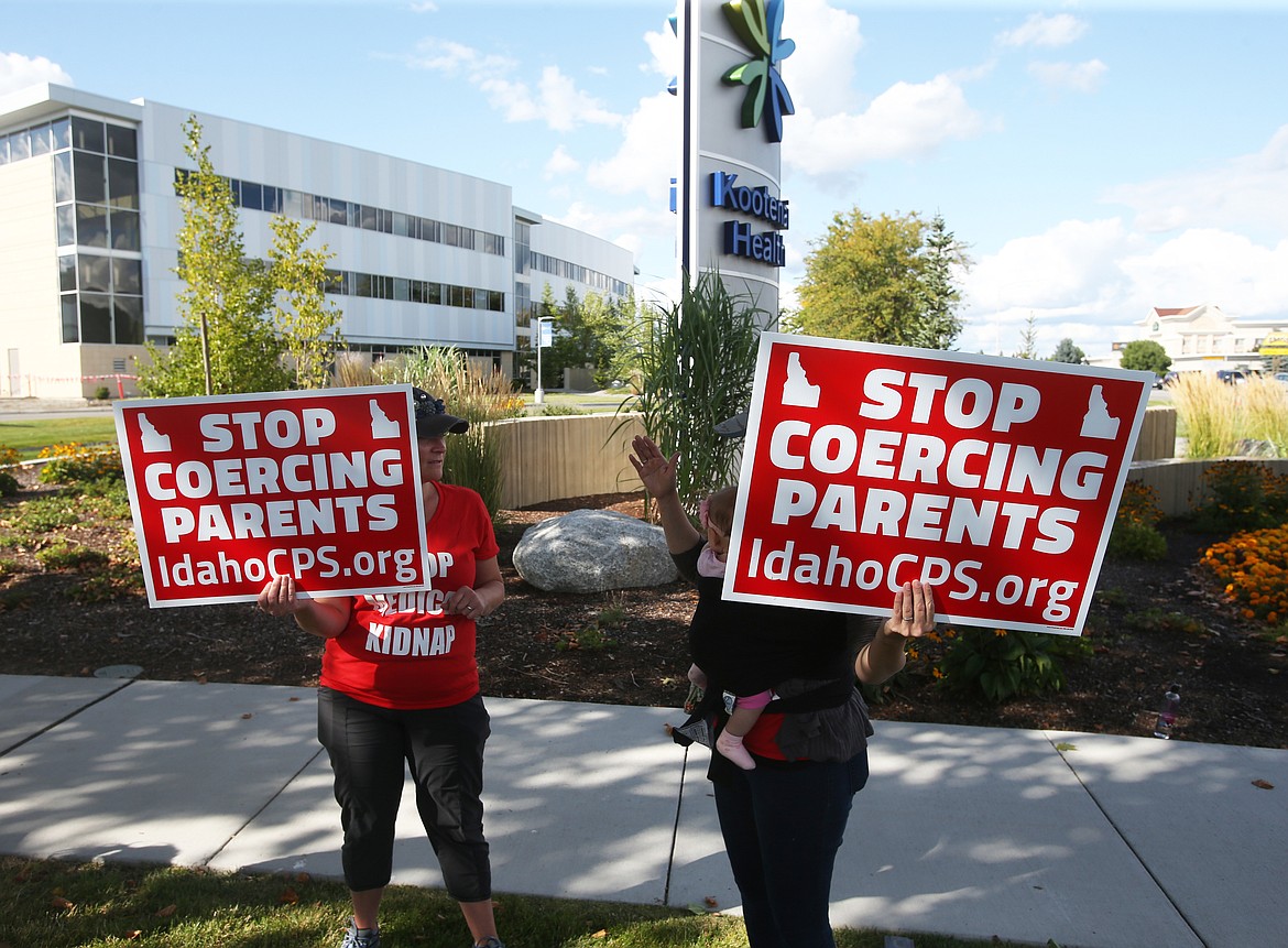 Two women hold signs next to Kootenai Health to voice their concerns about how Kootenai Health and CPS handle childcare treatment. (LOREN BENOIT/Press)