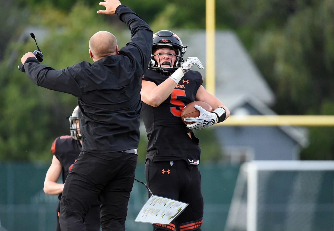 Flathead's Tannen Beyl (5) and Braves head coach Matt Upham celebrate after Beyl's first-quarter interception against Missoula Sentinel at Legends Stadium on Friday. (Casey Kreider/Daily Inter Lake)