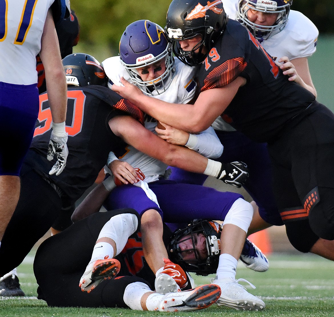 Flathead defenders Nolan White (35), Kayden Berkey (50) and Cole Dalager (79) wrap up Missoula Sentinel quarterback Dayton Bay (4) in the first half at Legends Stadium on Friday. (Casey Kreider/Daily Inter Lake)