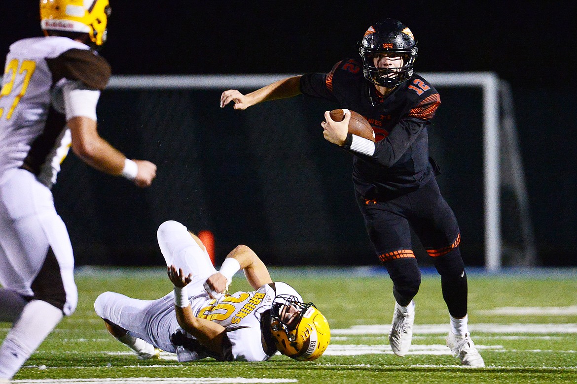 Flathead quarterback Cooper Smith (12) turns upfield after breaking the tackle of Helena Capital linebacker Kadyn Craigle (20) on a second quarter run at Legends Stadium on Friday. (Casey Kreider/Daily Inter Lake)