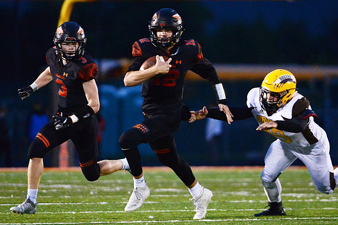 Flathead quarterback Cooper Smith (12) looks for running room against Helena Capital in the first quarter at Legends Stadium on Friday. At left is running back Chance Sheldon-Allen (3). (Casey Kreider/Daily Inter Lake)