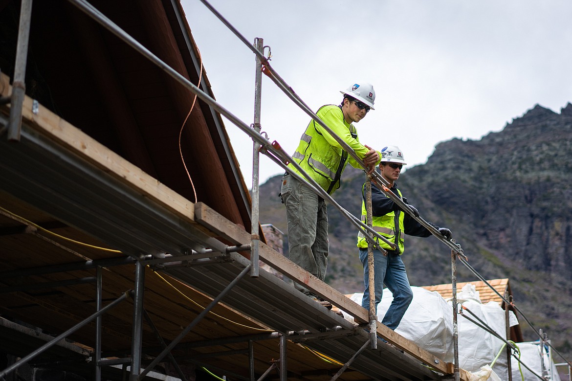 Construction workers from Dick Anderson Construction look out from the scaffolding on the Sperry Chalet roof. (Daniel McKay/Whitefish Pilot)