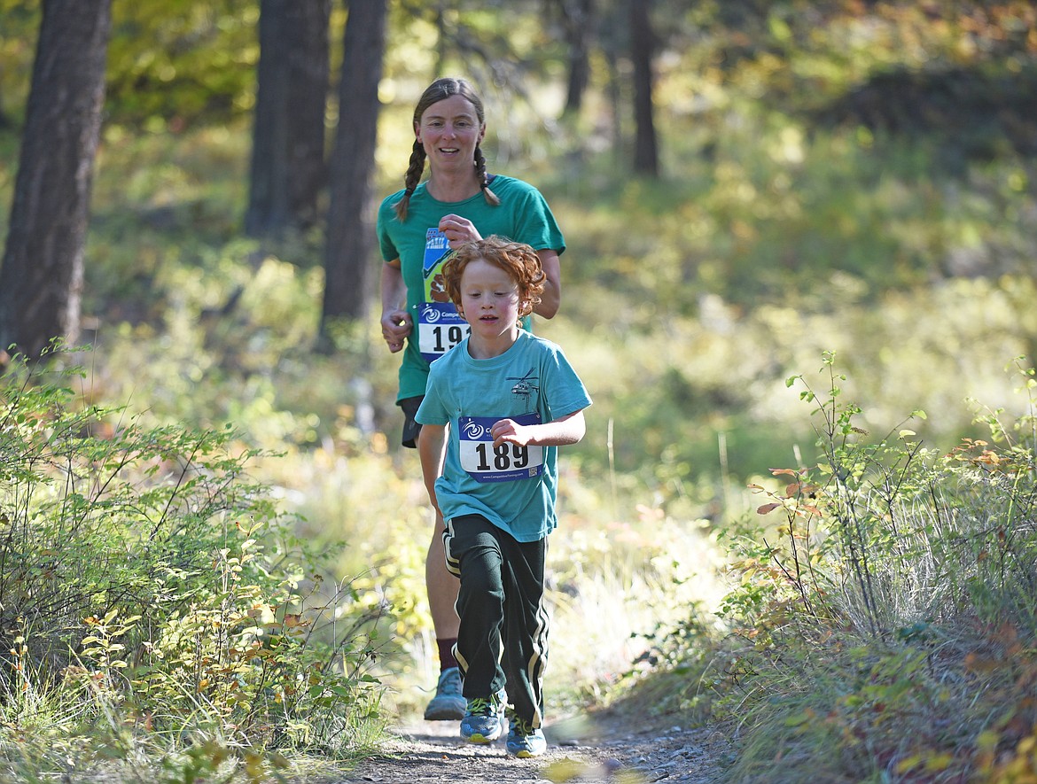 Wren Rosenkoetter, 7, and Jami Belt, both of Columbia Falls, run on the Whitefish Trail Sunday morning during the fun run of the Whitefish Trail Legacy Run. (Heidi Desch/Whitefish Pilot)