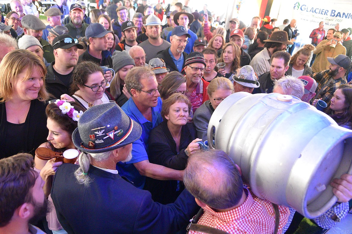 Folks crowd around to get a free stein of beer after the ceremonial tapping of the first keg Thursday night at the Great Northwest Oktoberfest. (Heidi Desch/Whitefish Pilot)