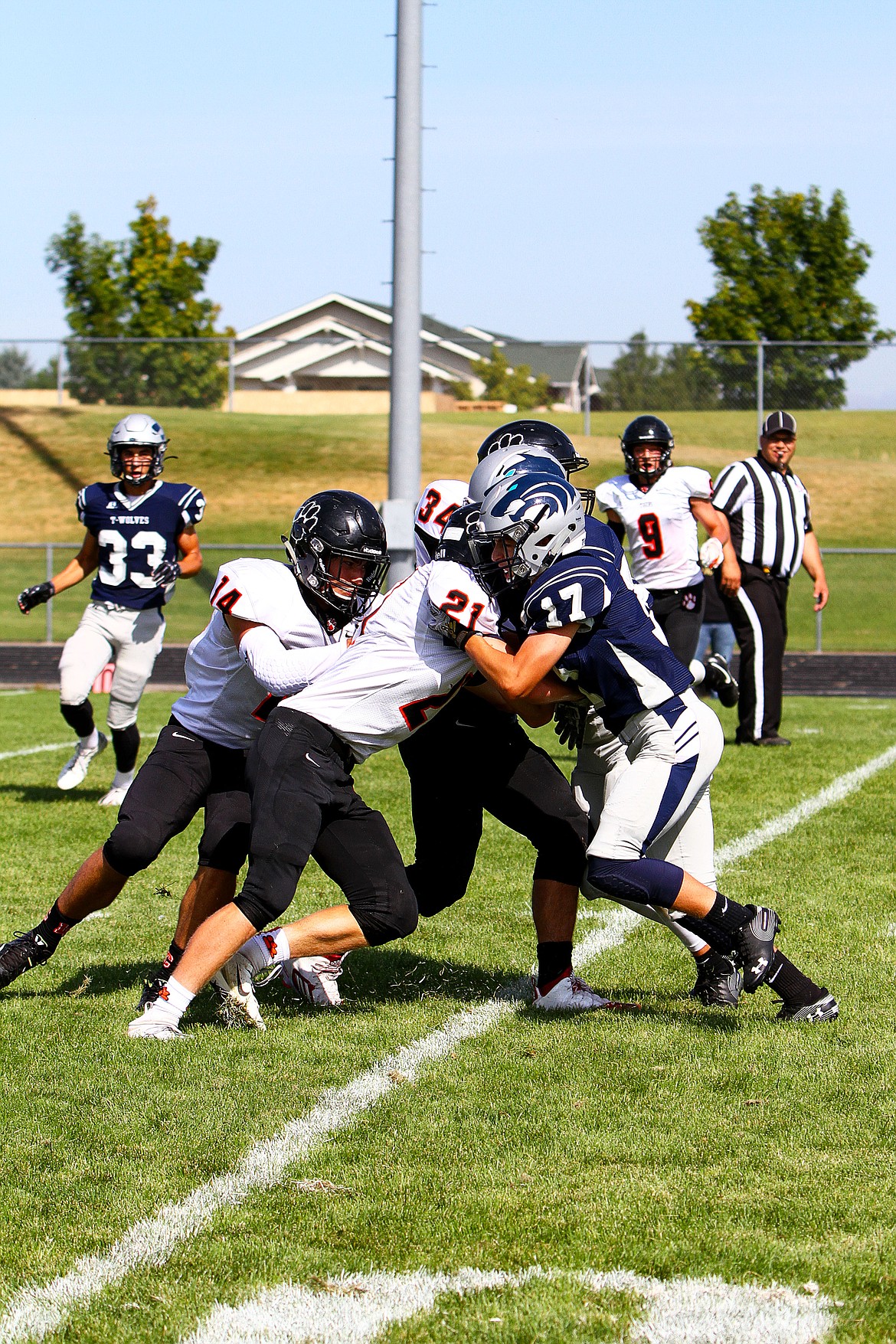 Daniel Close (14), Max Meyer (21) and Mathew Heer (34)  try to stop Zachary Adkinson (17) during a junior varsity football game between the Lake City High School Timberwolves and the Lewis and Clark Tigers on Saturday, Sept. 7 in Coeur dAlene.