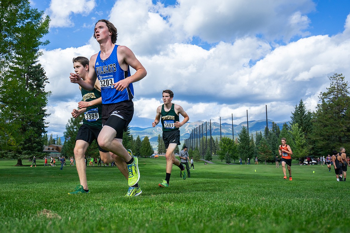 Jacob Bailey and Bridger Gaertner keep pace with a Wildcat runner during the Whitefish Invite last Tuesday at Whitefish Lake Golf Club. (Daniel McKay/Whitefish Pilot)