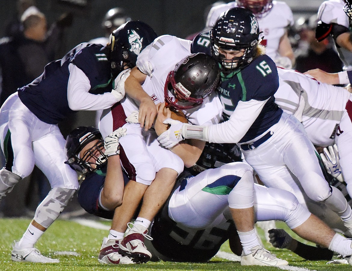 Glacier defenders Gator Mostek (11), Cole Johnson (31), Rocco Beccari (56) and Hunter Karlstad (15) wrap up Helena running back Logan Brown (26) in the first half at Legends Stadium on Friday. (Casey Kreider/Daily Inter Lake)