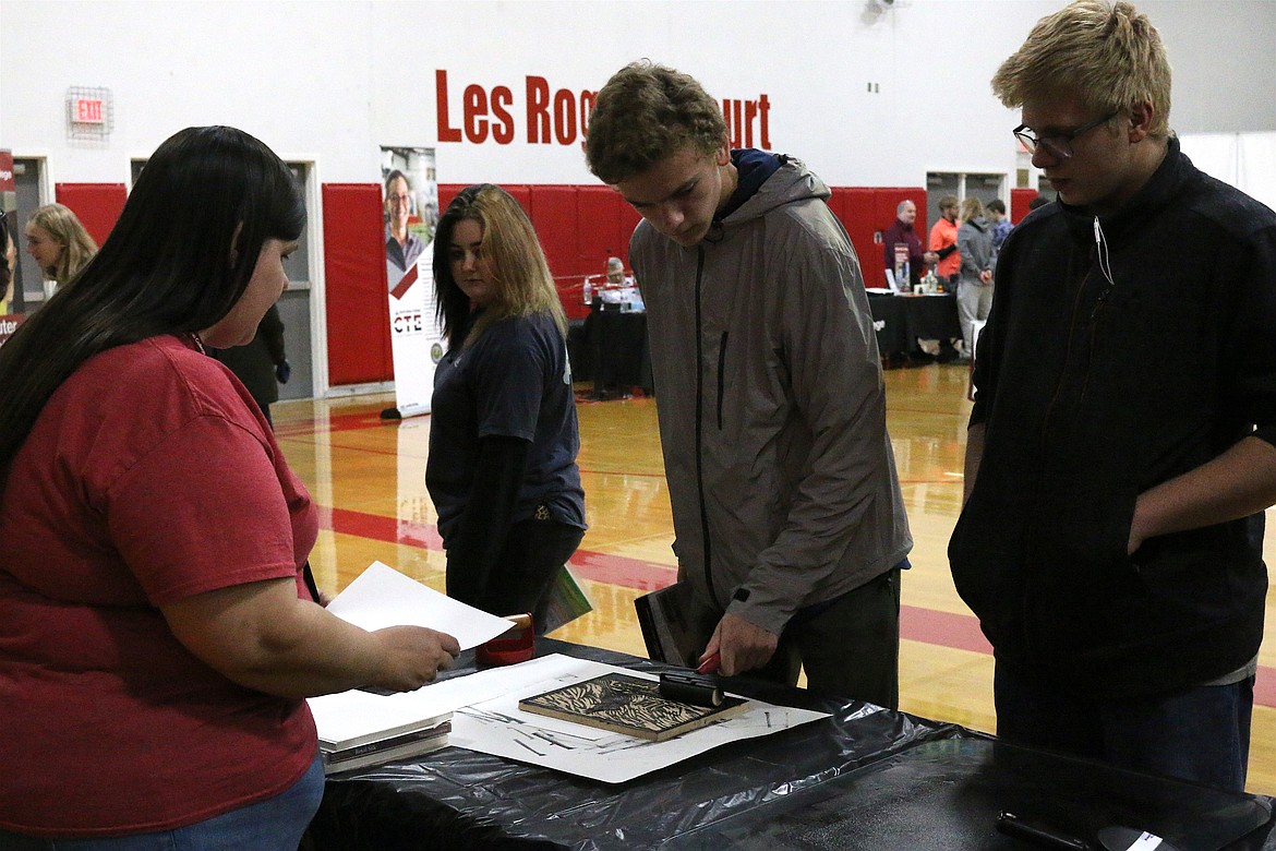 (Photo by MARY MALONE)
Lake Pend Oreille High School juniors Terrin Dustman, center, and Ethan Dieter, right, check out the communications and fine arts program during the North Idaho College CTE Roadshow and Sandpoint High School on Friday.