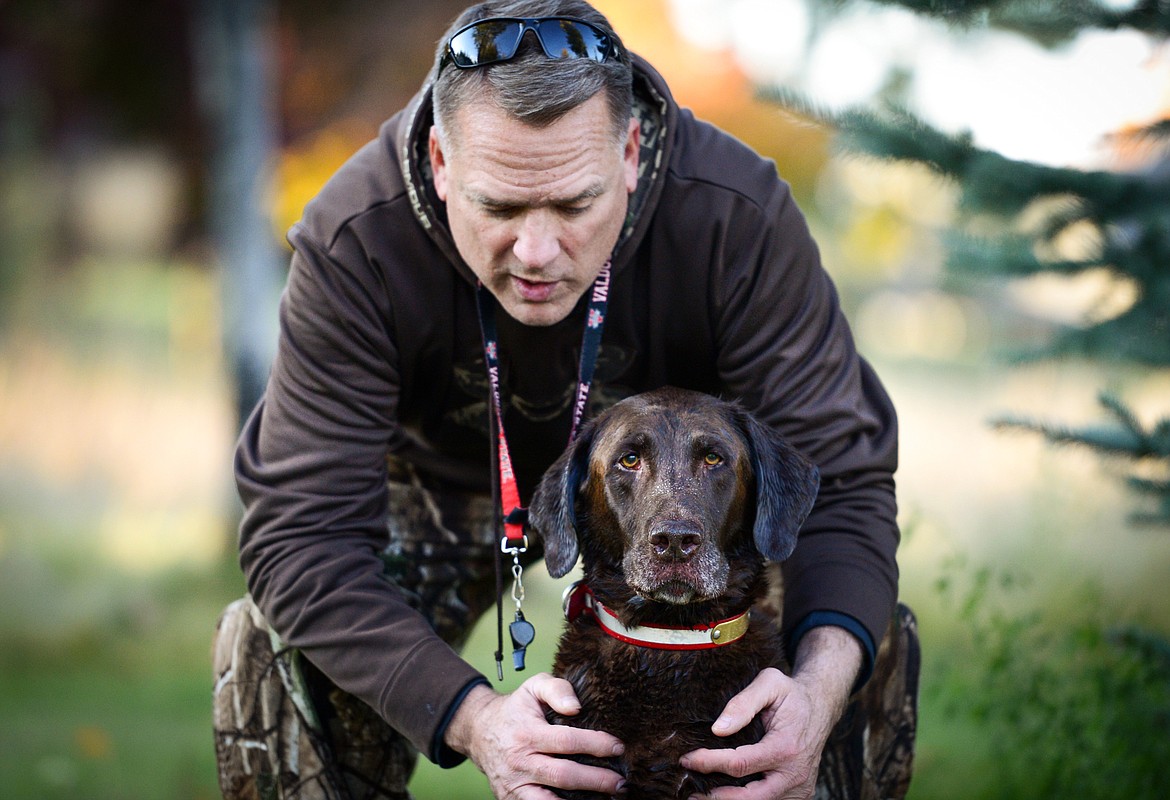 BILL Helfer speaks with Blazer, an 11-year-old chocolate Lab, during a training session for DockDogs.