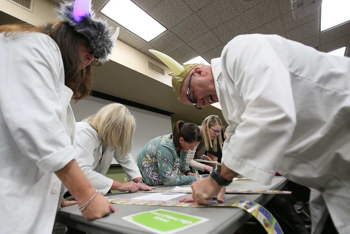 Coeur d'Alene High School science teacher Tim Burnside laughs as he gets through 150 scratch tickets at the Idaho Lottery's Scratch for Schools event Wednesday at North Idaho College. He and speech teacher Melody Melton, left, rocked the Viking horns to showcase their school pride. (DEVIN WEEKS/Press)