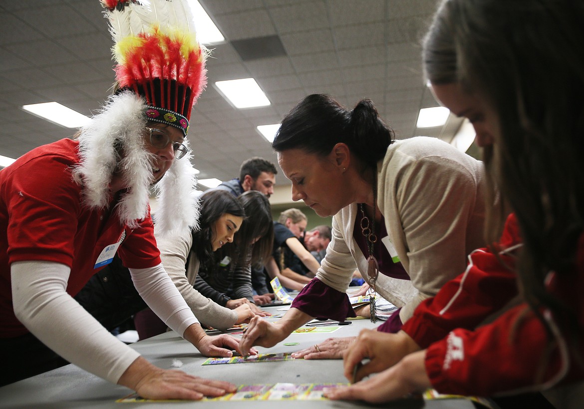 Harrison Elementary School fourth-grade teacher Shelley Bresnen, left, holds scratch tickets steady for Tess Davis, right, and Jill Pilloud, center, during the Scratch for Schools event Wednesday. (DEVIN WEEKS/Press)