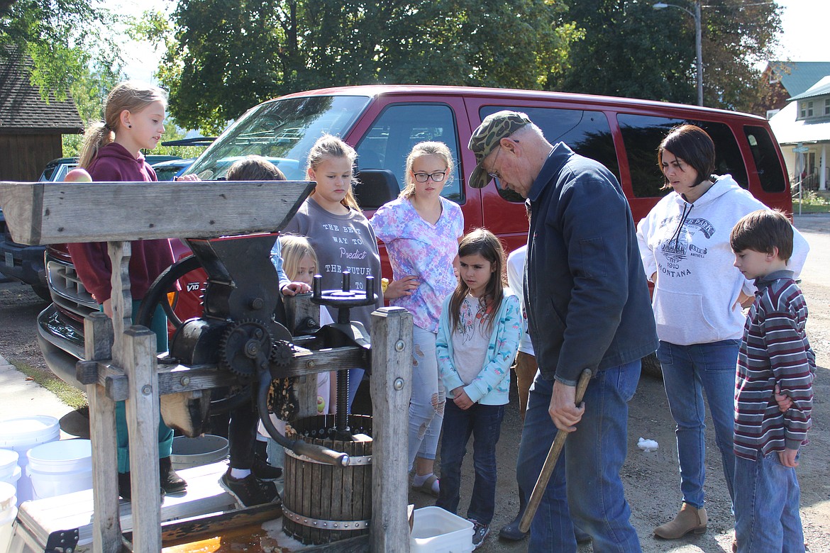 DENNIS OLSON helping the class of Facture Academy students use his apple press. (John Dowd/Clark Fork Valley Press)