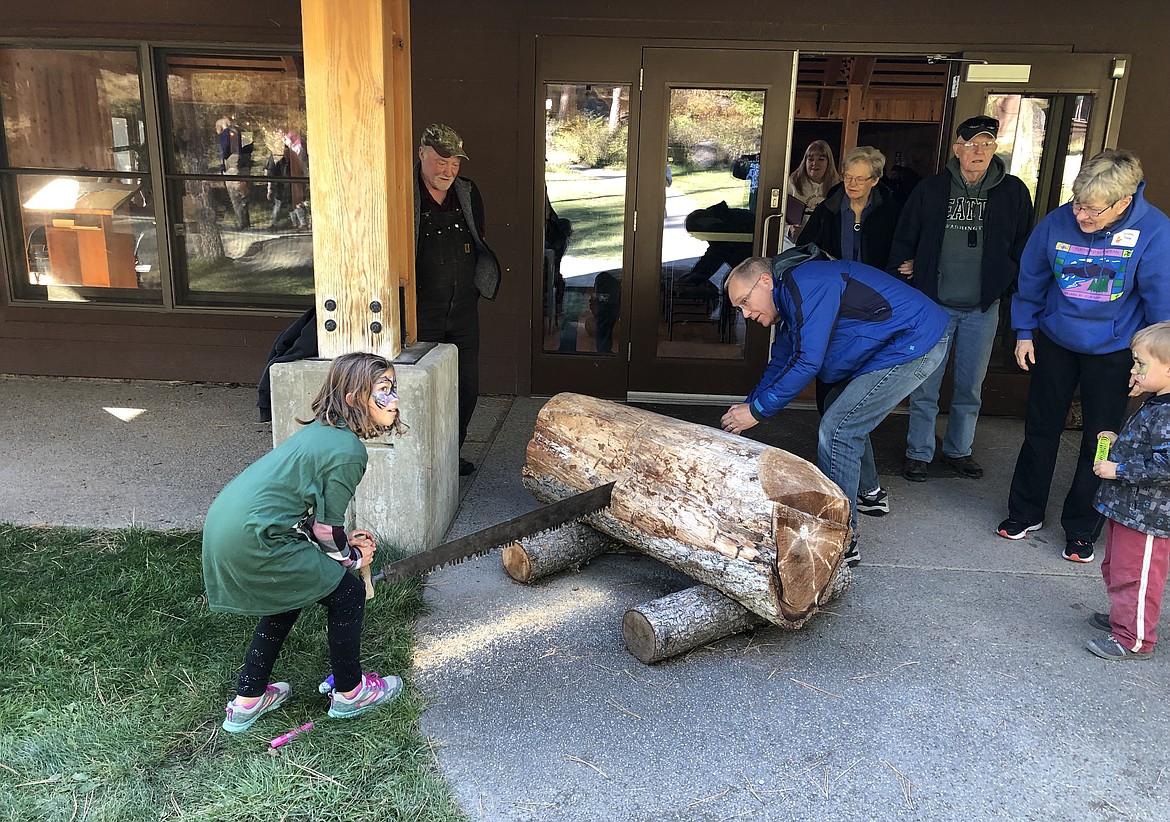 The Rev. Mike Borge of Missoula, a member of the Flathead Lake Bible Camp endowment committee, saws a log with camper Liana Janssen of Big Sandy as part of the dedication ceremony of the new Lakeview Cabin Complex. Cutting a log instead of a ribbon at a dedication ceremony is a unique tradition the camp started in recent years. &#147;We didn&#146;t think cutting a ribbon was fitting for a camp in the woods,&#148; said Margie Fiedler, executive director of Flathead Lutheran Bible Camp.