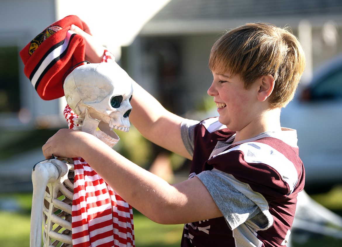 Joel Jones, 12, removes a scarf and cap from a skeleton after the snow storm as the family prepares for their new hunting scene motif on Friday evening, October 11.(Brenda Ahearn/Daily Inter Lake)