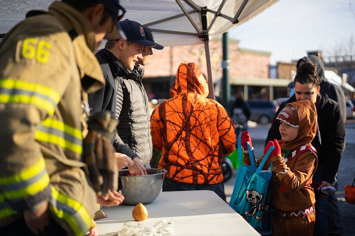 Members of the Whitefish Fire Department hand out candy during the Whitefish Trick or Treat downtown on Thursday. (Daniel McKay/Whitefish Pilot)