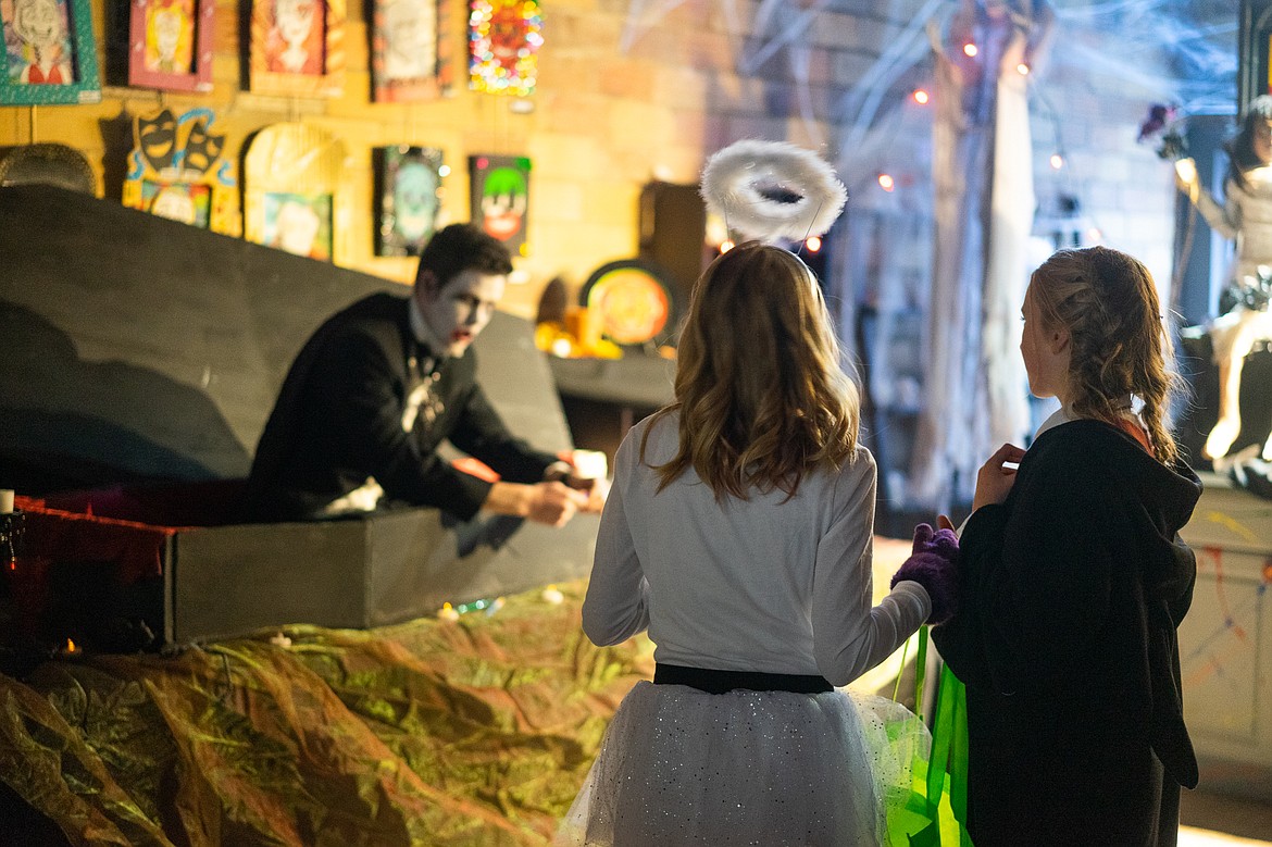 Two girls watch a man rise from the dead during the Whitefish Trick or Treat downtown on Thursday. (Daniel McKay/Whitefish Pilot)