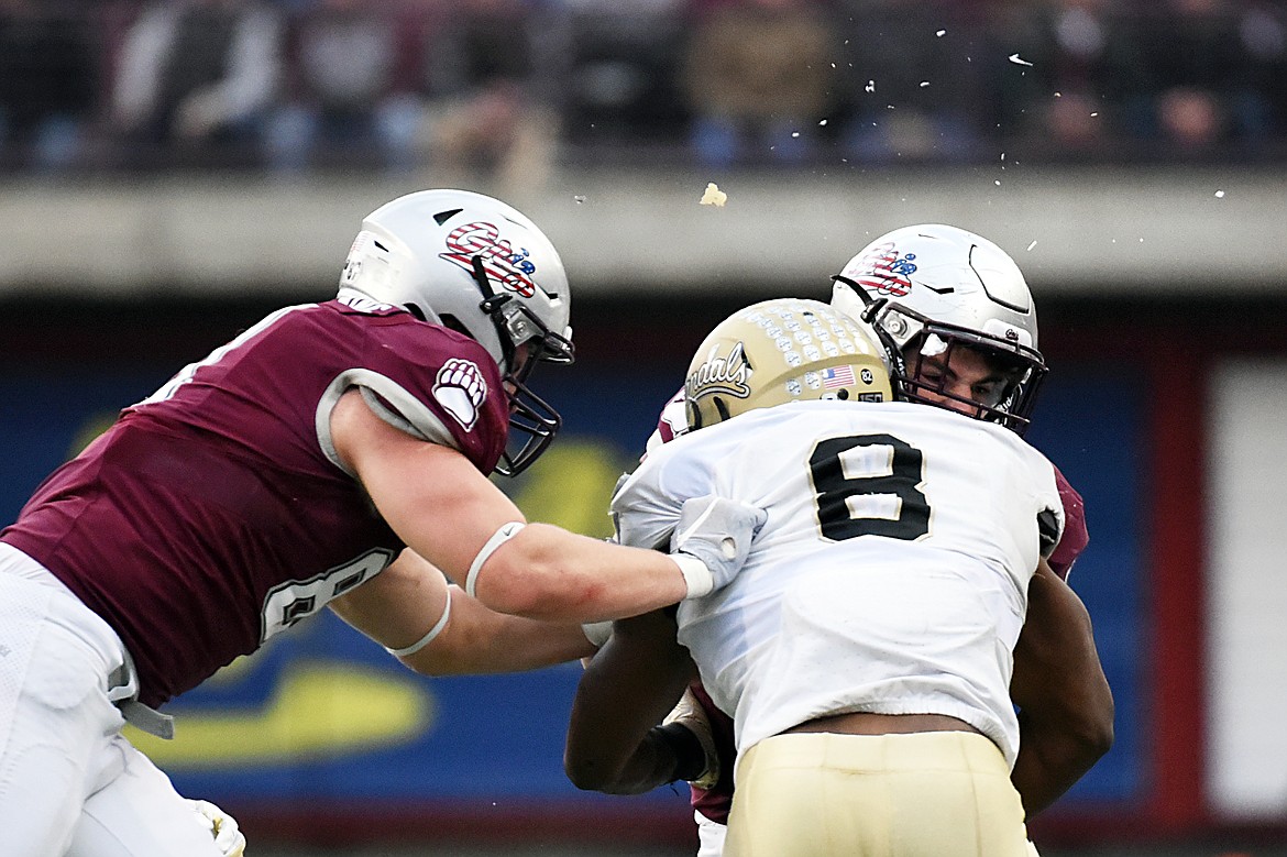 Pieces of a helmet go flying as Montana running back Nick Ostmo (38) collides with Idaho linebacker Tre Walker (8) on a fourth quarter run at Washington-Grizzly Stadium on Saturday. (Casey Kreider/Daily Inter Lake)