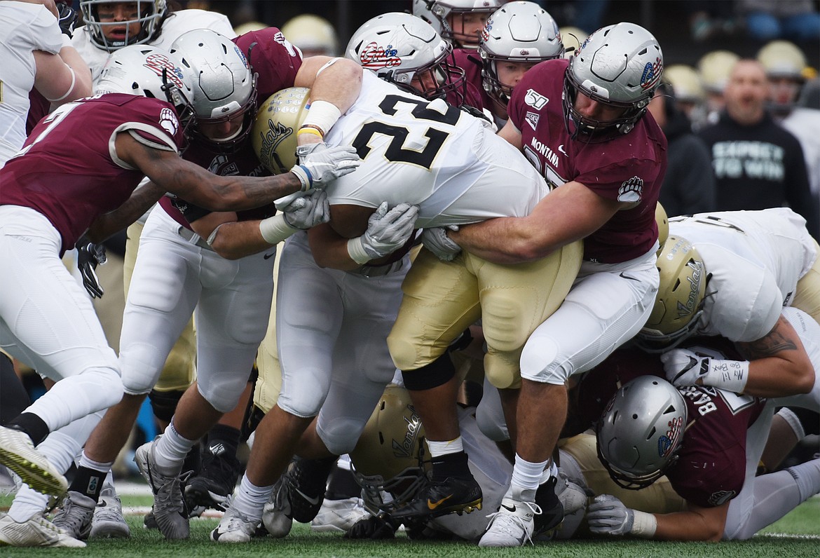 The Montana defense wraps up Idaho running back Aundre Carter (22) in the first quarter at Washington-Grizzly Stadium on Saturday. (Casey Kreider/Daily Inter Lake)