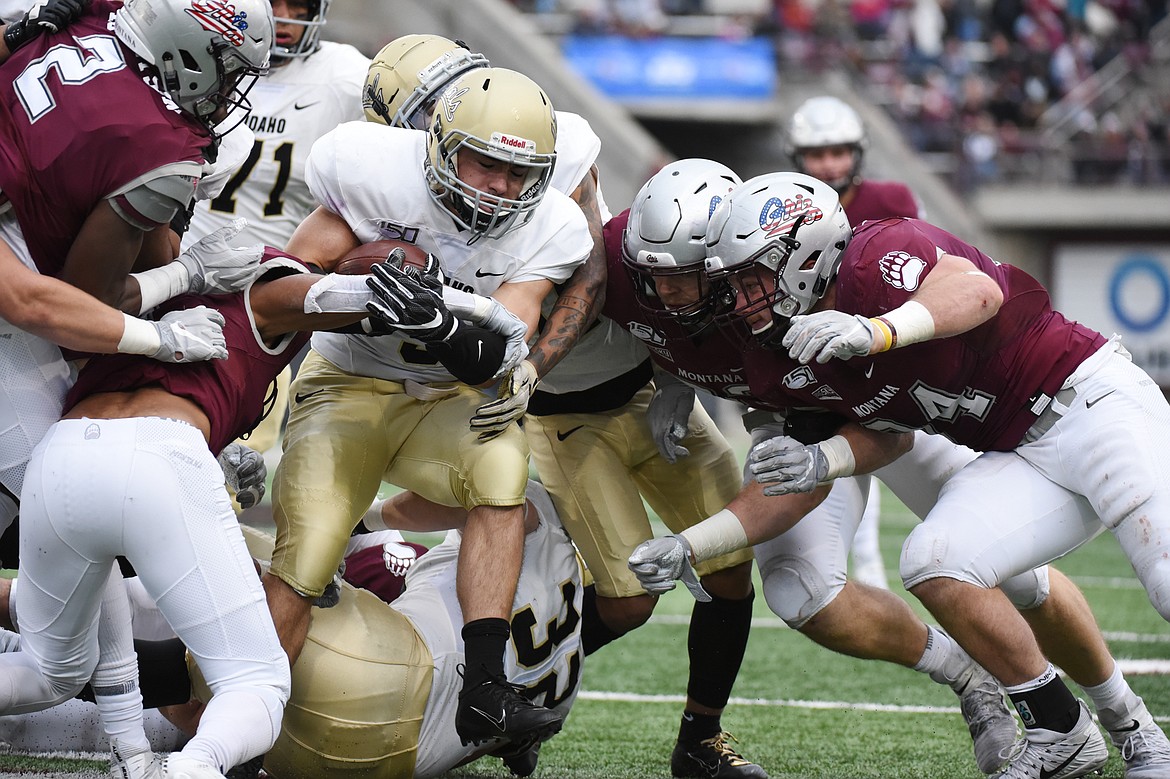 Montana defenders wrap up Idaho running back Nick Romano (3) in the first quarter at Washington-Grizzly Stadium on Saturday. (Casey Kreider/Daily Inter Lake)