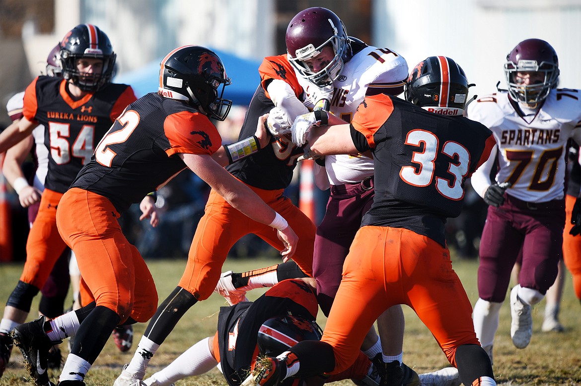 Baker running back Garrett Lesh (14) is wrapped up by Eureka defenders, from left, Ethan Holt (62), Grady Seal (57), Chet McCully (4) and Jake Kindel (33) on a run in the first quarter at Lincoln County High School in Eureka on Saturday. (Casey Kreider/Daily Inter Lake)