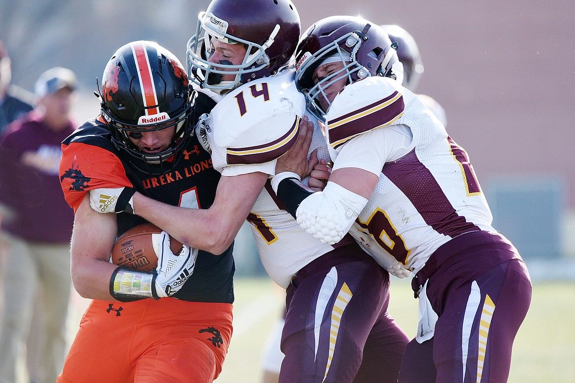 Eureka running back Chet McCully is forced out of bounds by Baker defenders Garrett Lesh (14) and Riley O'Donnell (16) on a run in the first quarter at Lincoln County High School in Eureka on Saturday. (Casey Kreider/Daily Inter Lake)