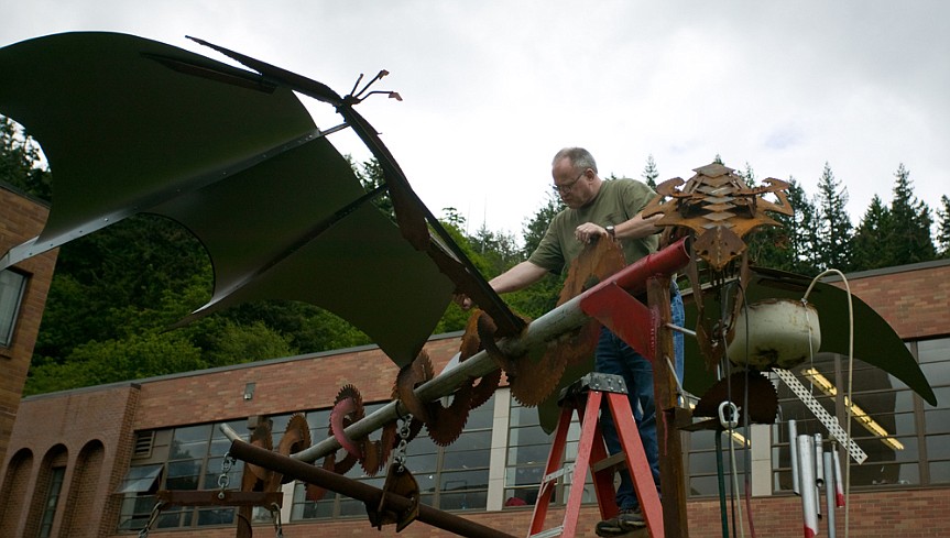 Photo courtesy of Western Washington University
Artist John Zylstra from 2013, while he secures a piece he created in front of the museum at Western Washington University. One of his more recent works, Marker #11, was ordered to be removed from its perch at Riverstone Park after public outcry for its display of the Soviet hammer and sickle.