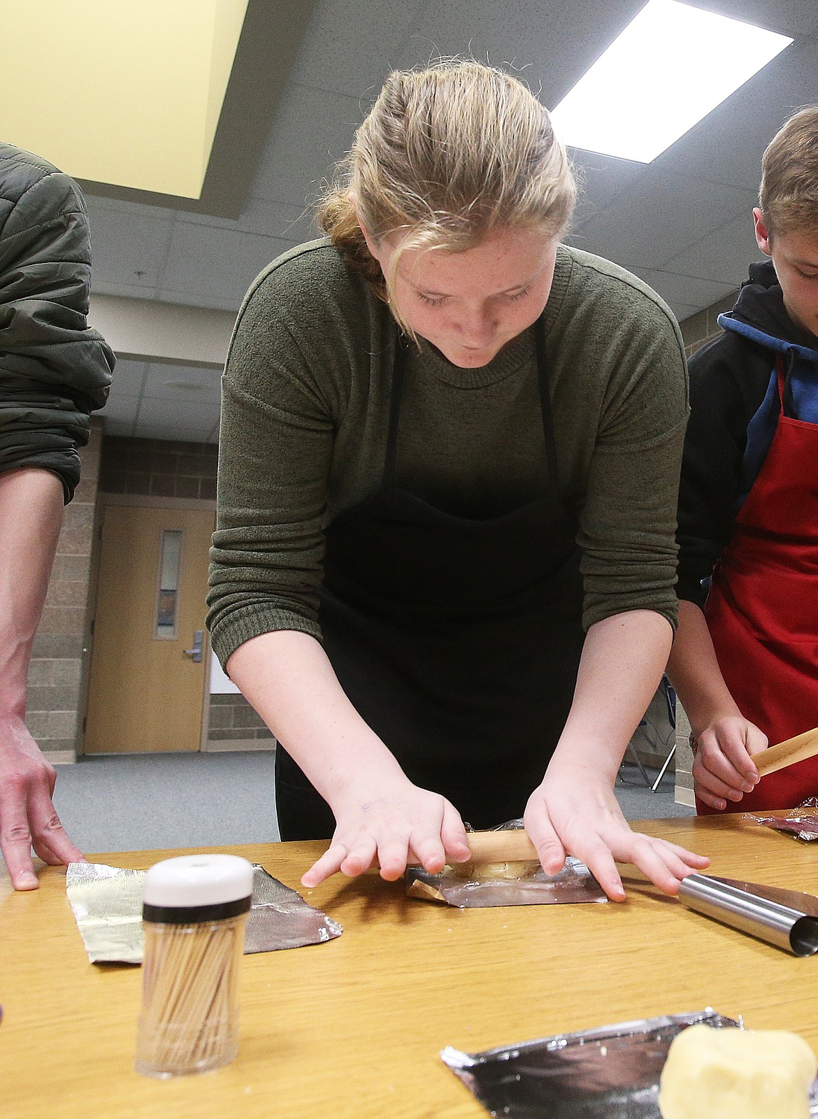 Seventh-grade student Rylee McHenry uses a roller to flatten cookie dough during a Teen Living course, which also helps students learn life skills like job interviewing and taking care of newborns.