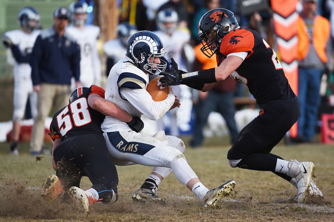 Eureka defenders Johnny Fehr (58) and Cory Chaney (25) sack Red Lodge quarterback Austin Heimer (2) in the third quarter in the State Class B semifinal at Lincoln County High School in Eureka on Saturday. Eureka won, 39-35. (Casey Kreider/Daily Inter Lake)