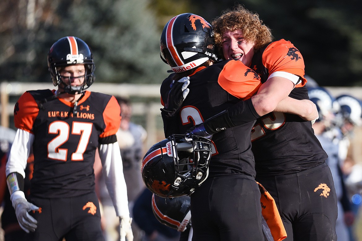 Eureka's Grady Seal (2) and Cory Chaney (25) hug after the Lions' 39-35 win over Red Lodge in the State Class B semifinal at Lincoln County High School in Eureka on Saturday. (Casey Kreider/Daily Inter Lake)