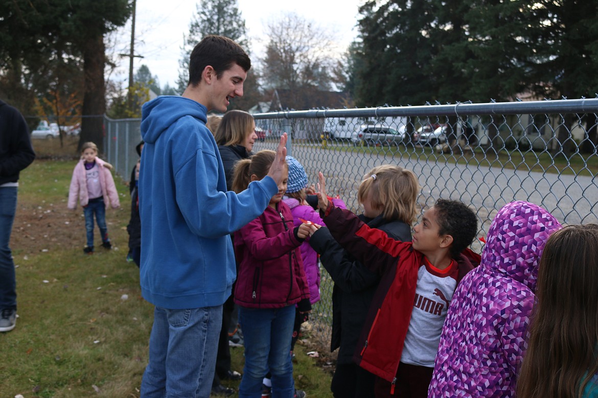 (Photo by MARY MALONE)
Priest River Lamanna High School sophomore Everett Hannah high fives an Idaho Hill Elementary student after helping the youngster tie a red ribbon to the fence in honor of National Red Ribbon Week.