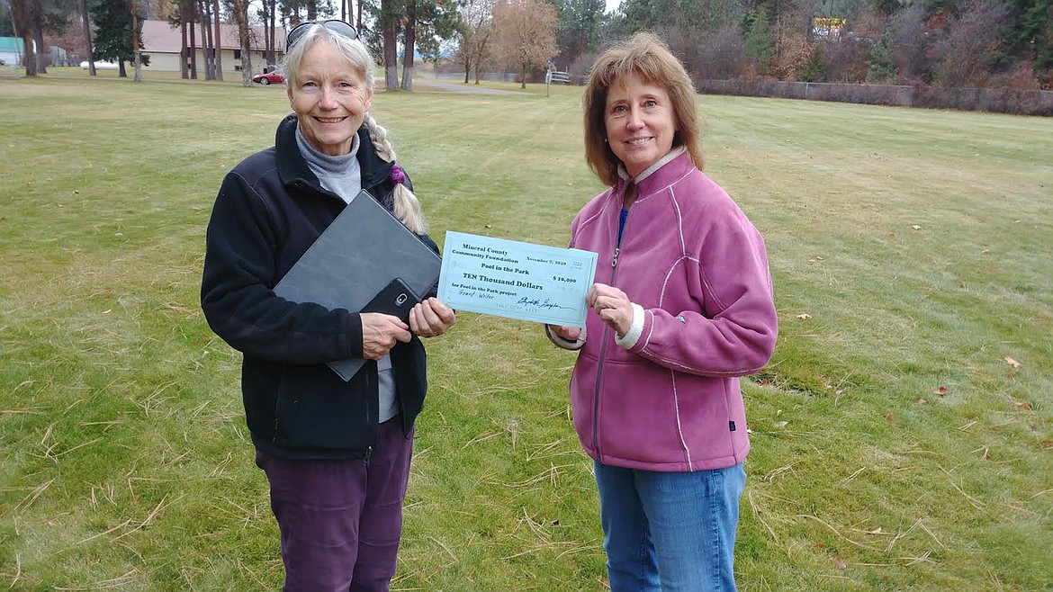 Liz Upton, President of the Mineral County Community Foundation, left, presents a replica check for $10,000 to Trish Donovan, a member of the Pool in the Park Committee. They are standing in the Superior public park near where the new pool would go.