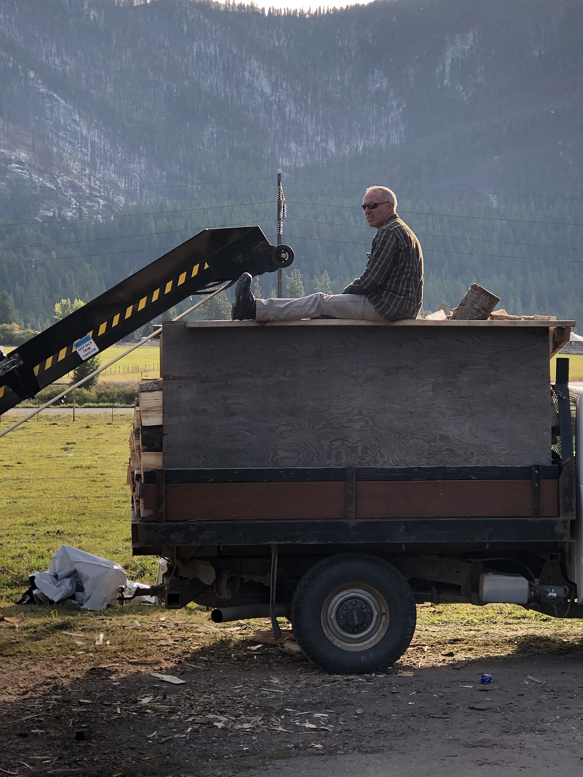 Jim Warnken rests atop a truckload of wood during a community volunteer effort to supply firewood to those whom needed the fuel for winter. (Photo by Lance Jasper)