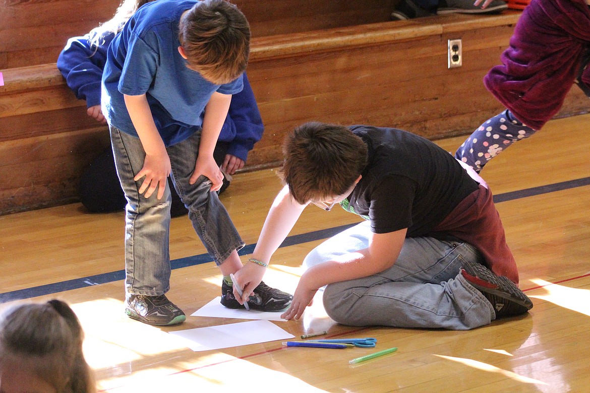 WYATT BROTHERTON tracing out a younger student&#146;s foot. (John Dowd/Clark Fork Valley Press)