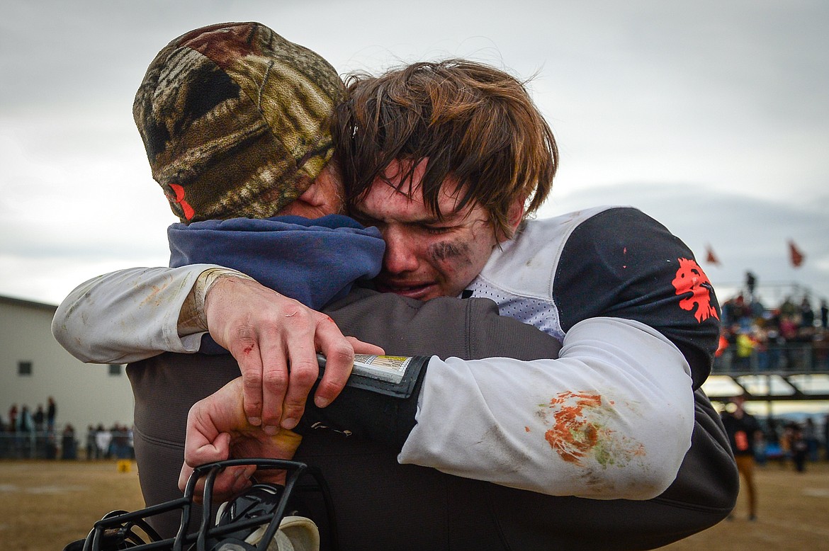 Eureka quarterback Hank Dunn (5) gets a hug from his father and Lions&#146; assistant coach Chad Dunn after a 20-6 victory over Manhattan in the Class B State Championship in Manhattan on Saturday. (Casey Kreider/Daily Inter Lake)