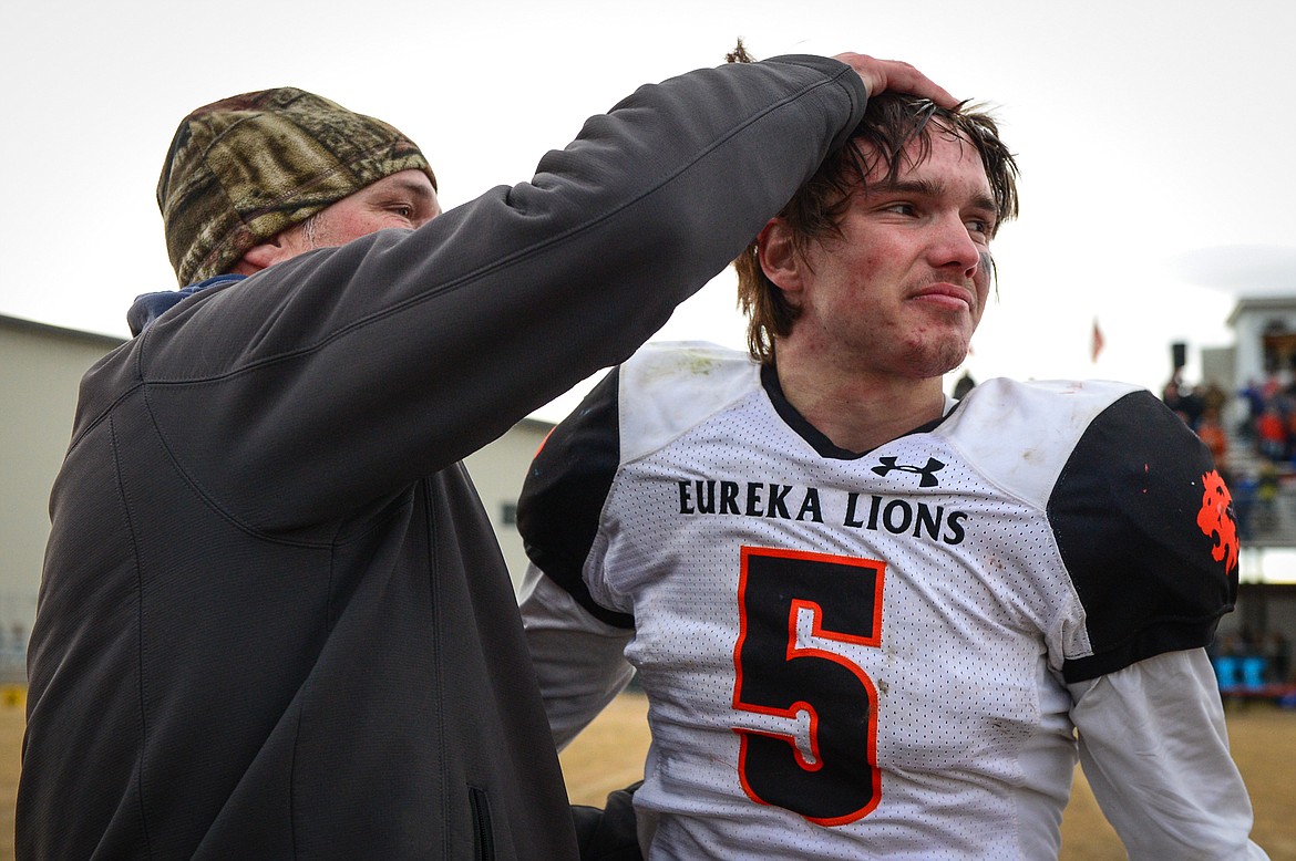 Eureka quarterback Hank Dunn (5) celebrates with his father and Lions' assistant coach Chad Dunn after a 20-6 victory over Manhattan in the Class B State Championship in Manhattan on Saturday. (Casey Kreider/Daily Inter Lake)