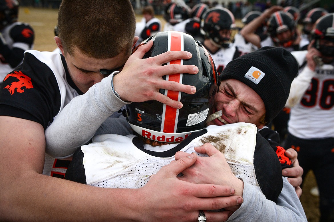 Eureka's Sean Bernhard (50, left) and Chet McCully (4, right) hug quarterback Hank Dunn (5) after the Lions defeated Manhattan 20-6 in the Class B State Championship in Manhattan on Saturday. (Casey Kreider/Daily Inter Lake)