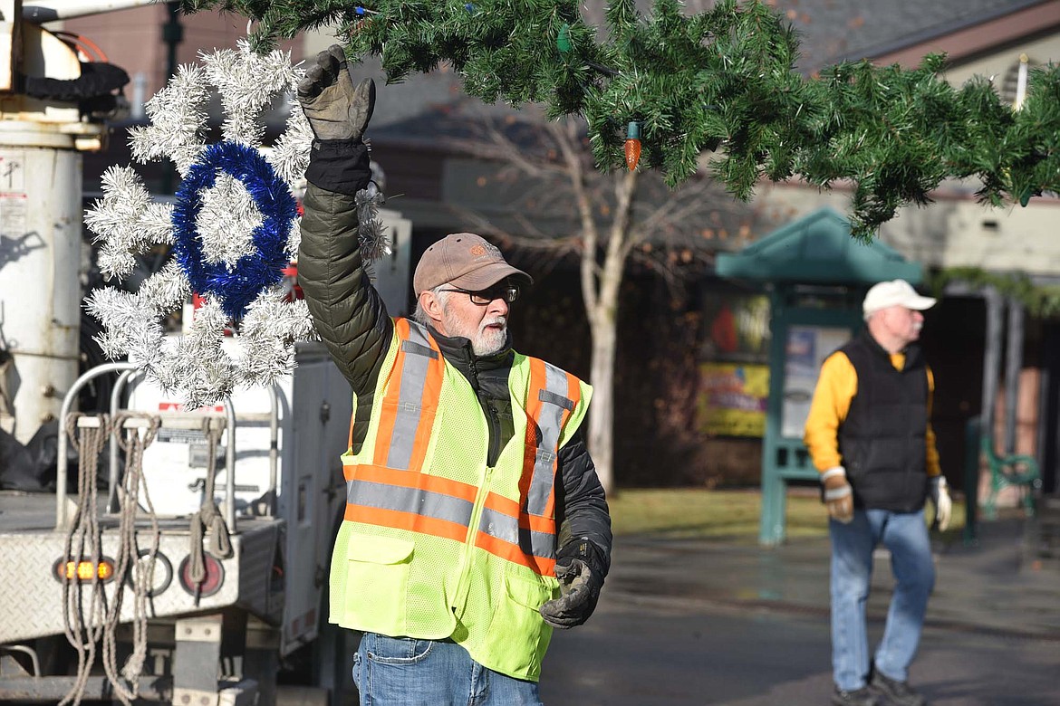 Mike Muldown lets go as a section of garland is lifted Sunday morning near Depot Park. (Heidi Desch/Whitefish Pilot)