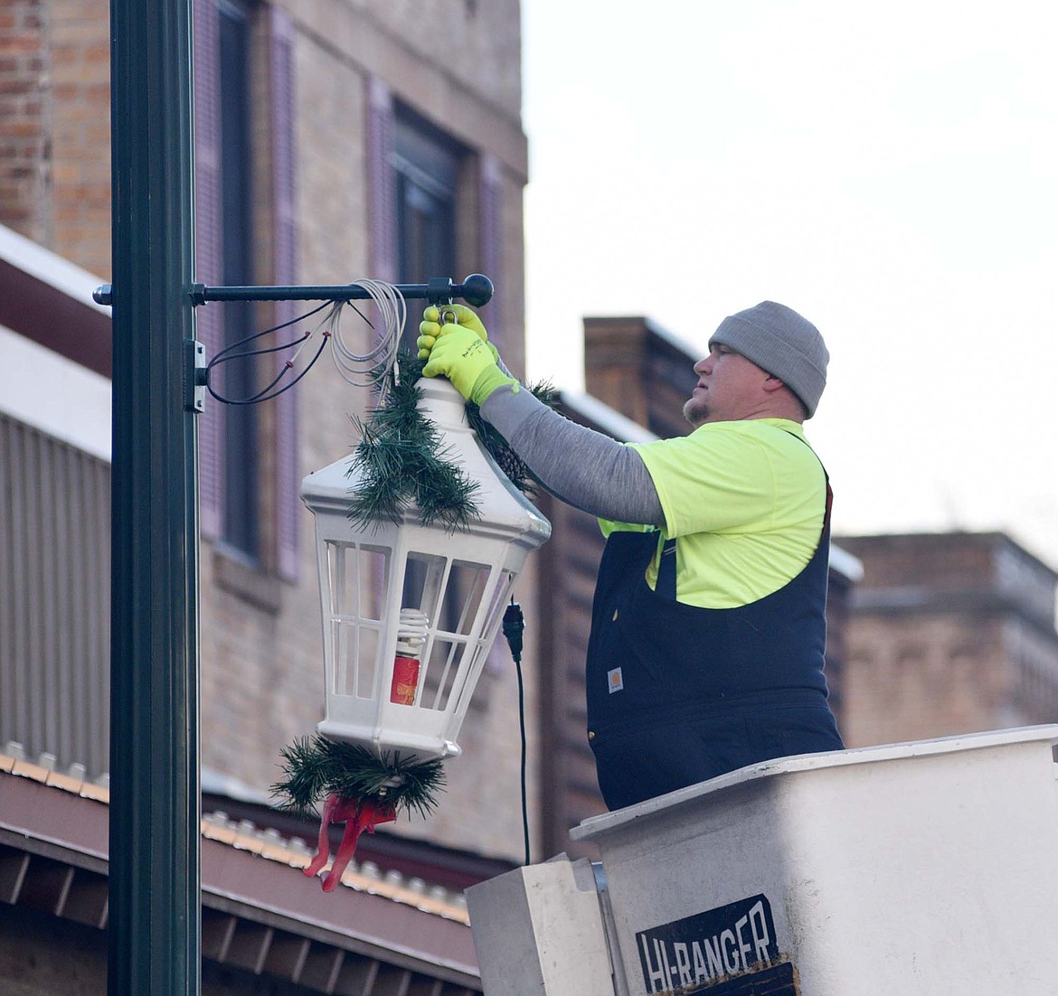 Josh Gansel, with the City of Whitefish, attaches a lantern to a light pole on Central Avenue downtown Sunday morning. (Heidi Desch/Whitefish Pilot)