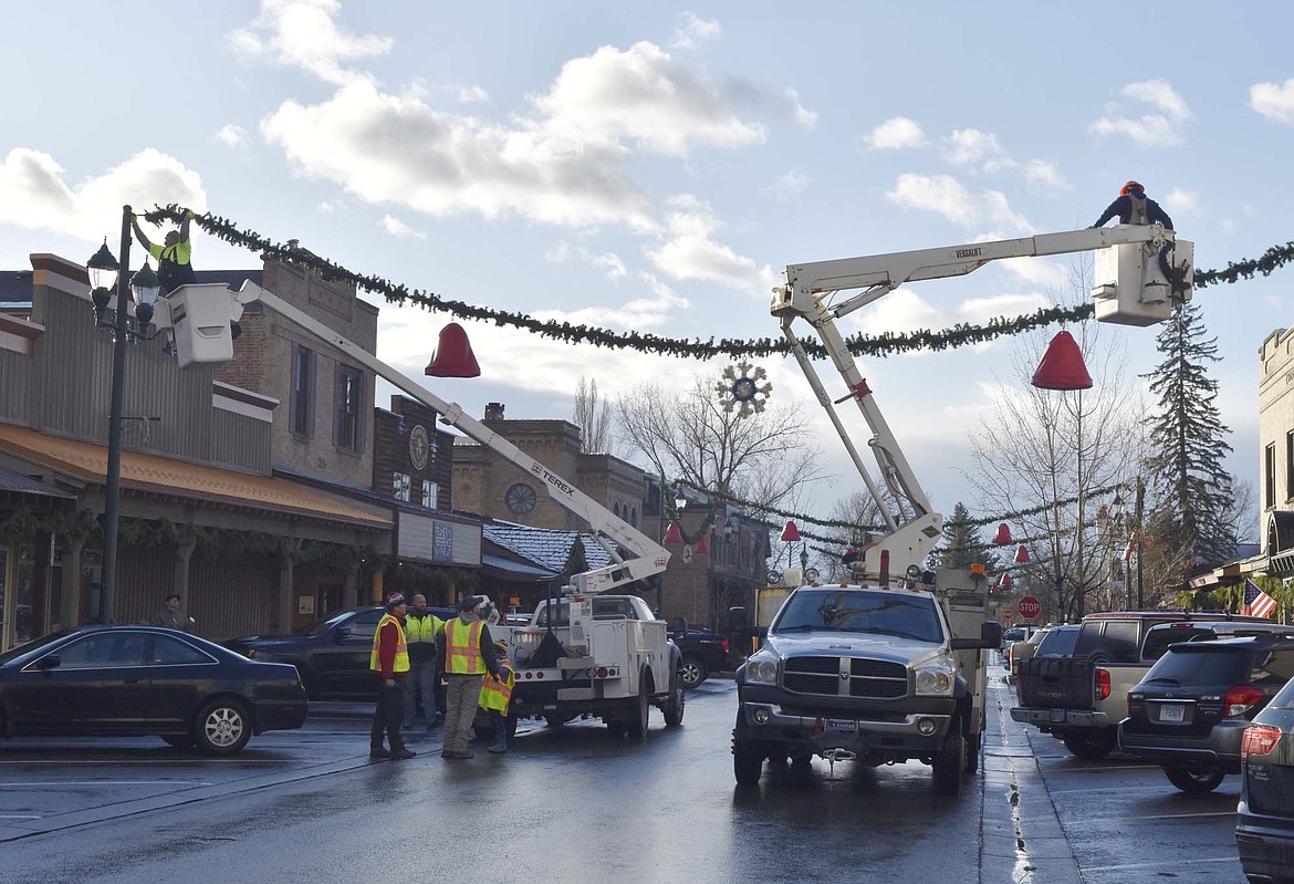 Volunteers hang the winter decorations downtown Sunday morning. (Heidi Desch/Whitefish Pilot)