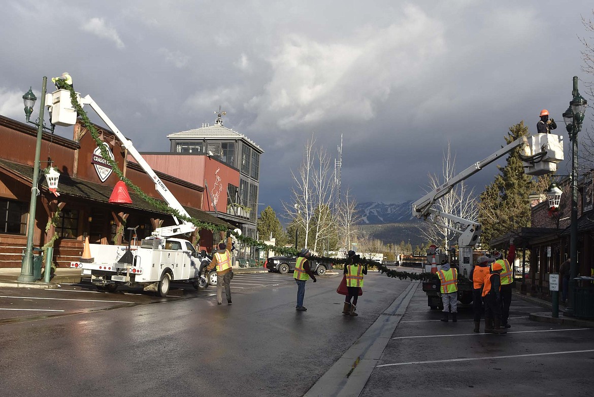 Volunteers hang the winter decorations downtown Sunday morning. (Heidi Desch/Whitefish Pilot)