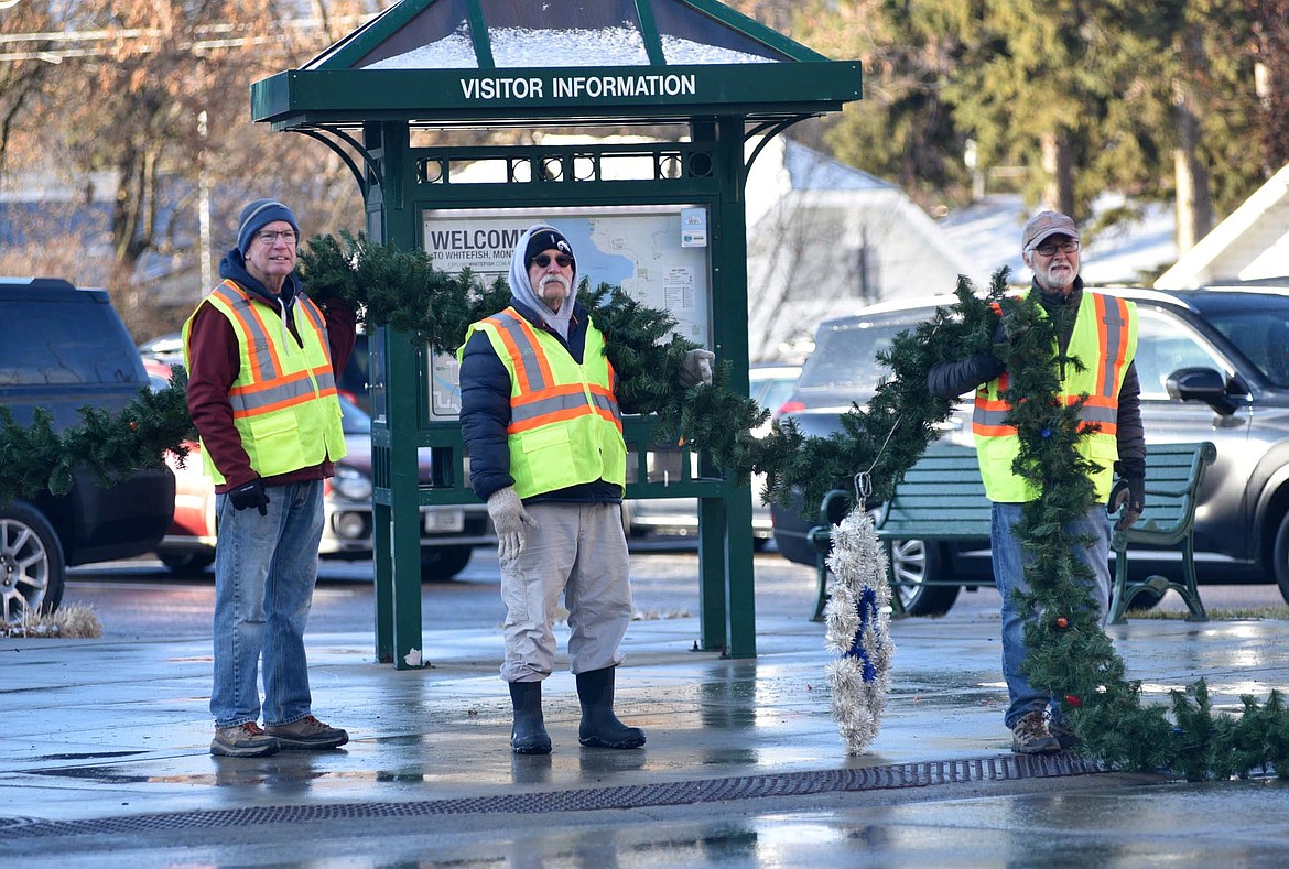 Volunteers hang the winter decorations downtown Sunday morning. (Heidi Desch/Whitefish Pilot)