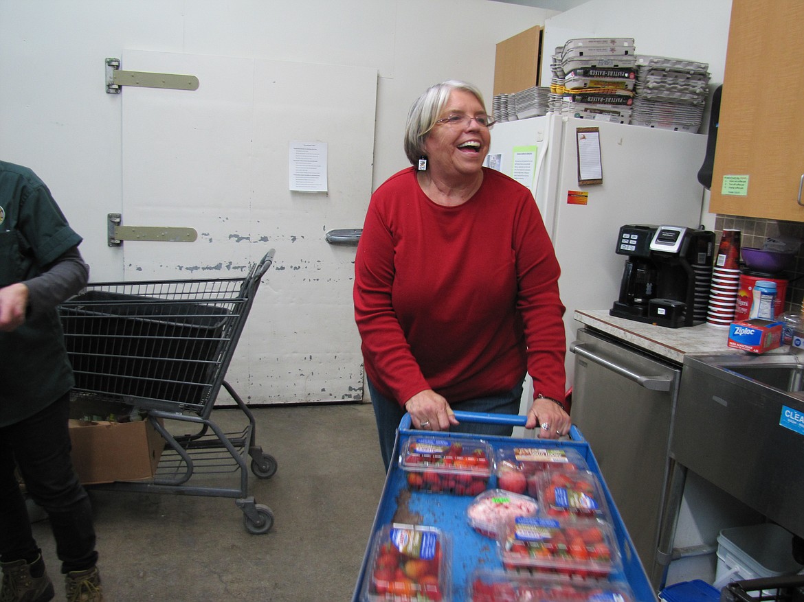 Post Falls Food Bank volunteer Judy Kline wheels a cart of strawberries to the produce section.