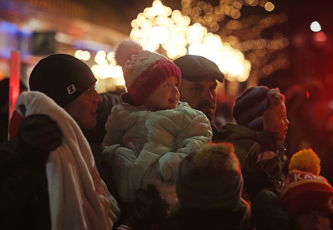 Chris Schuman, left, of Missoula, holds his daughter Kellynn, 3, as they watch Santa make his way down the Holiday Parade route Friday on Sherman Avenue. (LOREN BENOIT/Press)