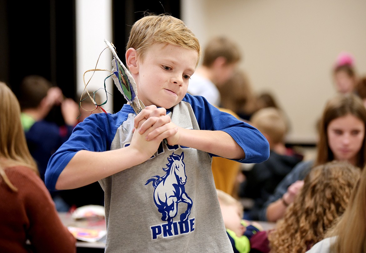 Aiden Skees, a seventh-grader, helps out by using a hole punch on the thick hand-made paper project some of the first grade students in their Indian Education For All project on Thursday, Nov. 21. (Brenda Ahearn/Daily Inter Lake)